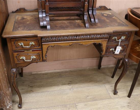 An Edwardian carved mahogany writing table with leather skiver